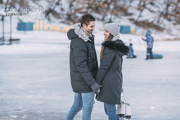 Glückliches Paar steht auf der Eisbahn