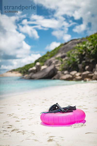 Tauchflossen mit Tauchermaske und aufblasbarem Ring am Strand gegen bewölkten Himmel  Seychellen