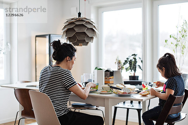 Mother and daughter having food at dining table