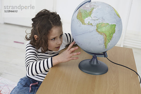 Nahaufnahme eines Mädchens  das den Globus auf dem Tisch der Vorschule erkundet.
