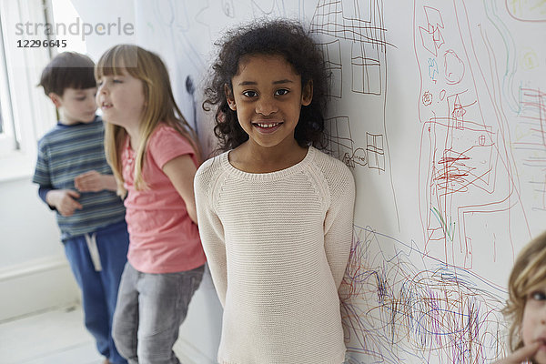 Porträt eines Mädchens  das mit Freunden gegen Zeichnungen an der Wand steht.