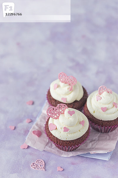 Rote Samt-Cupcakes mit Frischkäse und rosa Zuckerherzen