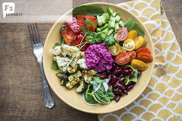 Schüssel mit Salat  gebratenem Gemüse  Bohnen und Rote-Bete-Hummus