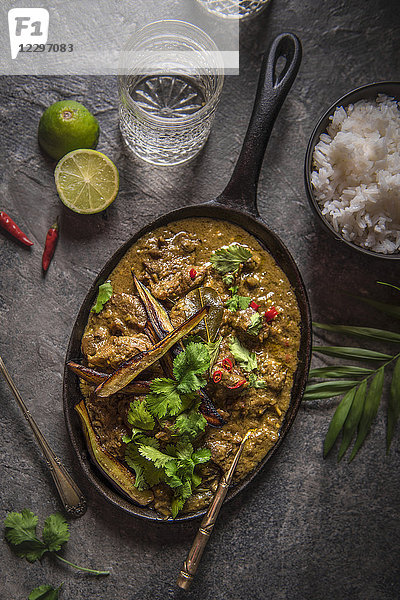 Rindfleisch-Rendang-Curry  langsam gekocht mit Zitronengras  Limettenblättern  Gewürzen und Kokosnusscreme  garniert mit knusprigen Auberginen und frischem Koriander