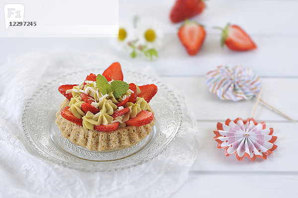 Erdbeertorte mit Mandelkeksen und Pistaziencreme  dekoriert mit frischen Erdbeeren und weißer Schokolade (vegan)