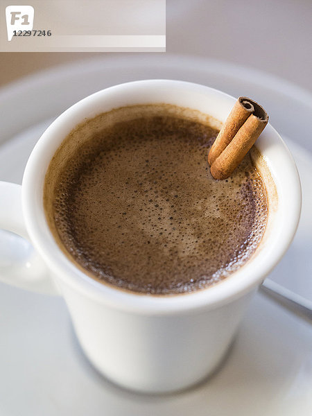 Portugiesischer Kaffee  serviert in einer Tasse mit Zimtstange (Nahaufnahme)