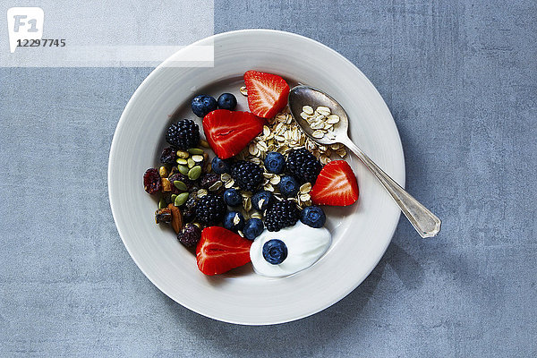 Haferflocken  Beeren mit Joghurt und Samen zum Frühstück auf einem Teller über grauem Vintage-Hintergrund