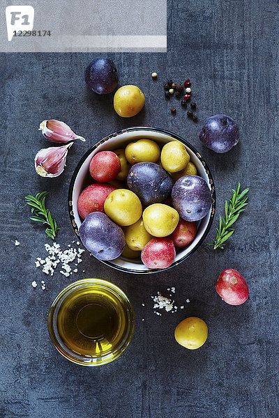 Kochen Hintergrund mit frischen Kartoffeln  Knoblauch und Olivenöl über dunklen Grunge Tisch