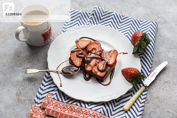 Eine Scheibe Roggenbrot mit Erdbeeren belegt und mit Schokoladensoße beträufelt