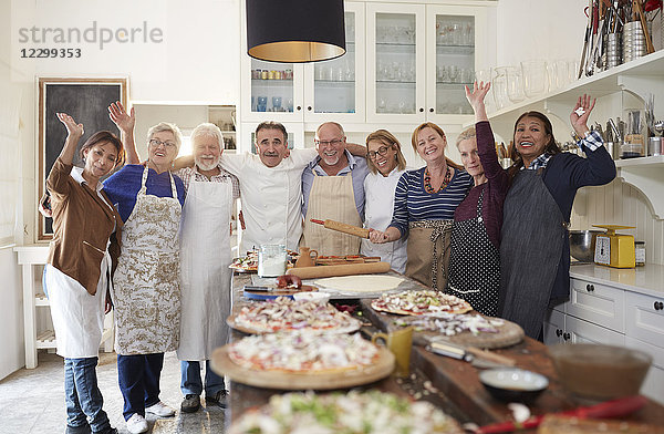 Portrait confident active senior friends and chef taking pizza cooking class