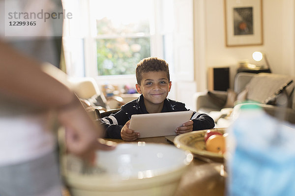 Portrait smiling boy using digital tablet in kitchen