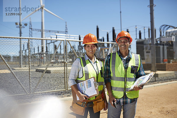 Portrait smiling  confident engineers with clipboards at power plant