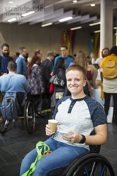 Portrait smiling  confident young woman in wheelchair drinking coffee at conference