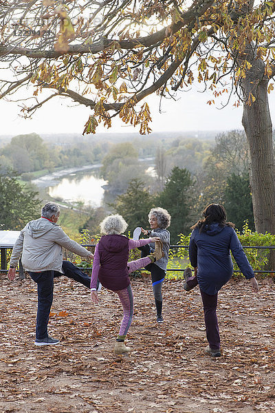 Active seniors stretching  exercising in autumn park