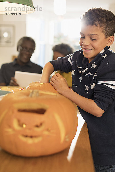 Smiling boy carving Halloween pumpkins