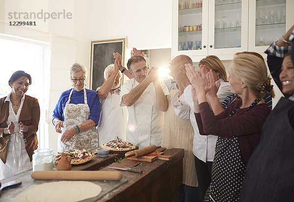 Chef and active senior friends clapping in pizza cooking class