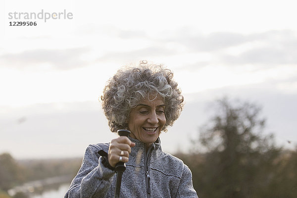 Smiling active senior woman hiking with pole