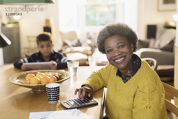 Portrait smiling senior woman paying bills at dining table