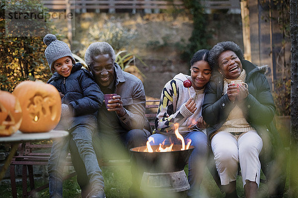 Grandparents and grandchildren enjoying autumn backyard campfire