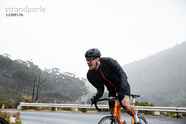 Determined male cyclist powering uphill