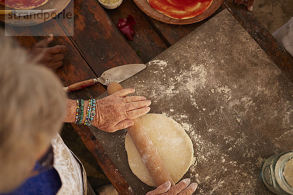 Overhead view senior woman rolling  making fresh pizza dough