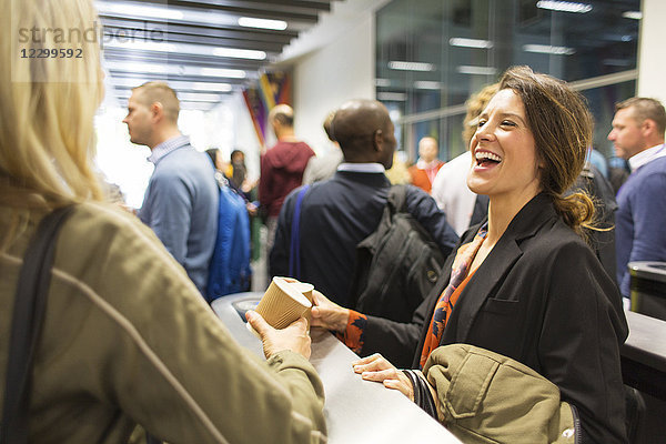 Laughing businesswomen drinking coffee at conference