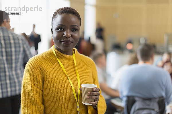 Portrait confident businesswoman drinking coffee at conference