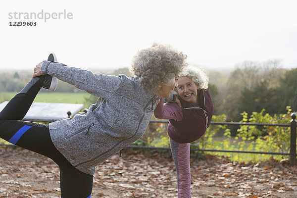 Active senior women friends stretching  practicing yoga in autumn park