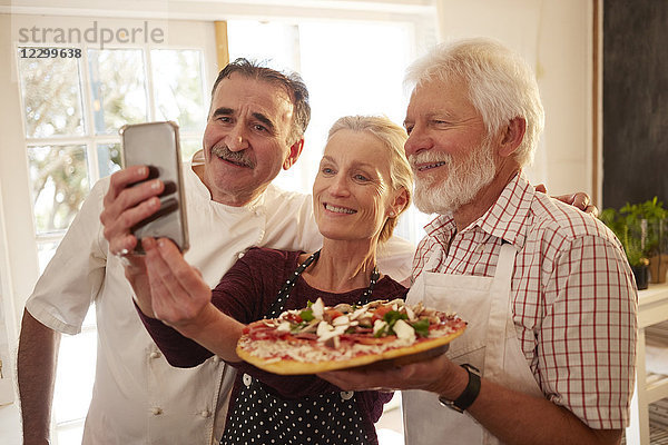 Chef and senior couple taking selfie with pizza in cooking class