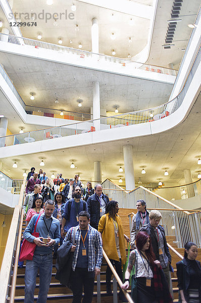 Business people descending stairs in modern lobby atrium
