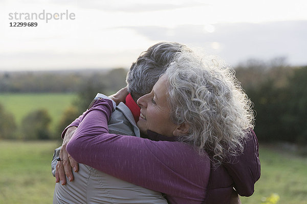 Affectionate senior couple hugging in field