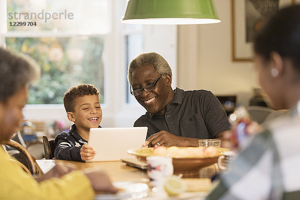 Smiling grandfather and grandson using digital tablet