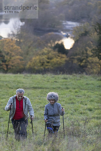 Active senior couple hiking up rural hillside