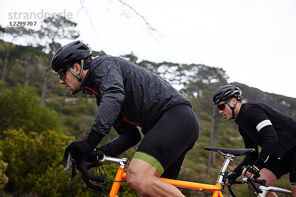 Focused  determined male cyclist cycling uphill