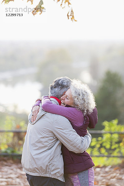 Affectionate active senior couple hugging in park