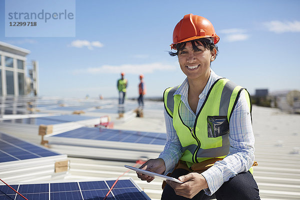 Portrait smiling  confident female engineer with digital tablet inspecting solar panels at sunny power plant
