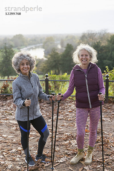 Portrait smiling  confident active senior women friends hiking with poles in autumn park