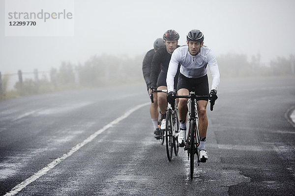 Dedicated male cyclists cycling on rainy road