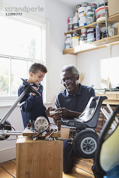 Grandfather and grandson assembling go-cart in garage