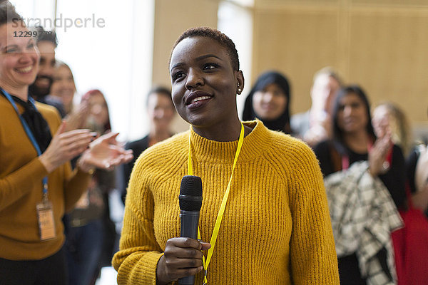 Smiling businesswoman speaker with microphone at conference
