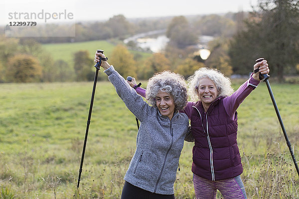 Portrait confident  enthusiastic active senior women friends hiking with poles in rural field