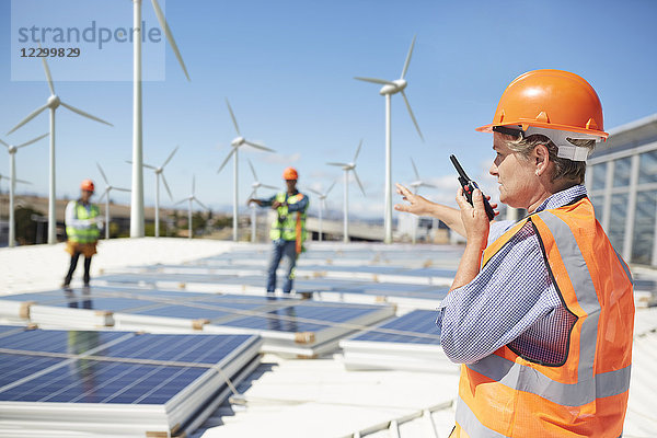 Female engineer using walkie-talkie at alternative energy power plant