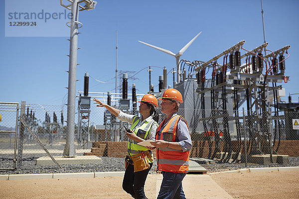 Female engineers with digital tablet at sunny power plant