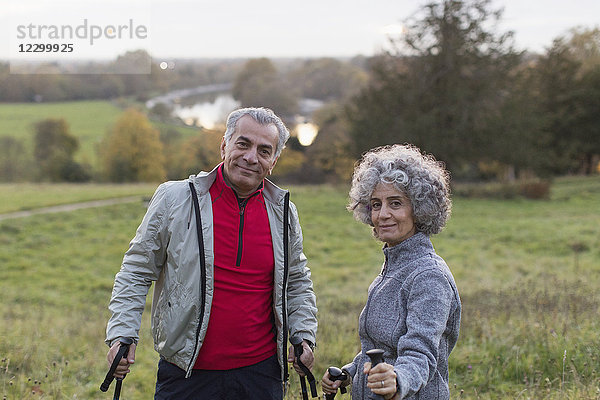 Portrait confident active senior couple hiking in rural field