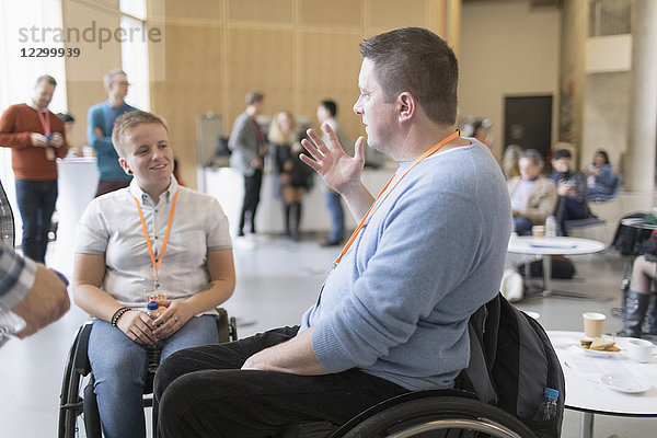 Business people in wheelchairs talking at conference