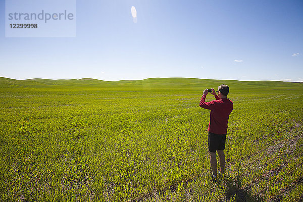 Tourist beim Fotografieren einer Landschaft auf einer grünen Wiese  Palouse  Washington State  USA