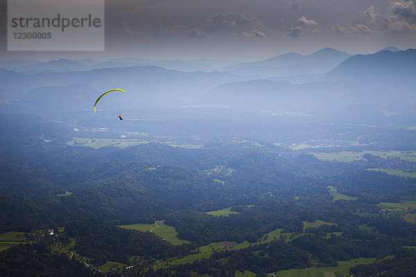 Fernblick auf einen Gleitschirm  der hoch über dem Gebirgstal von Begunje und Radovljica fliegt  nachdem er vom Berg Dobrca gestartet ist  Oberkrain  Slowenien