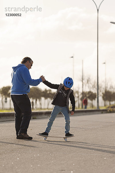 Vater bringt seinem kleinen Sohn das Skateboardfahren bei