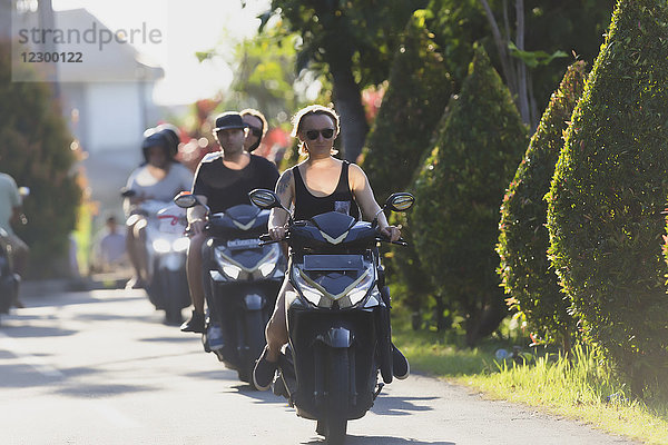 Vorderansicht einer jungen Frau  die eine Reihe von Menschen auf Motorrädern anführt