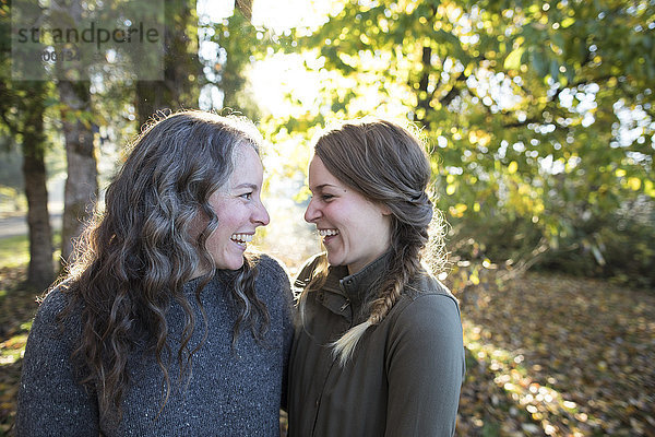 Zwei lachende Freundinnen von Angesicht zu Angesicht im Park